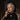 Close-up of the woman's face with a smoking cigar and a lace cap. The Velvet Matriarch