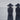 Close-up of two women in black coats and wide-brimmed hats, seen from behind, facing the sea. Three Quiet Oaths