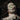Close-up of a face in a clay mask, with a moustache and cucumber slices over the eyes. Velvet Vanity Hour