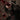 Close-up of a hand holding a wine glass with red wine splashing out, against a black lace dress. Burgundy Verdict